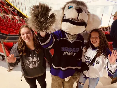 OSDSS Wolves mascot and two people waving