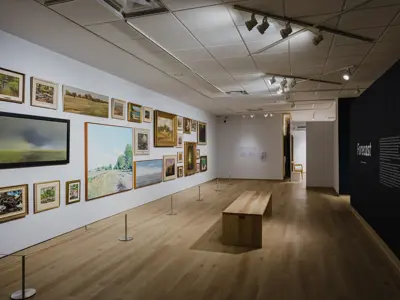 Wide view of the Forecast exhibition with landscape artworks and bench.