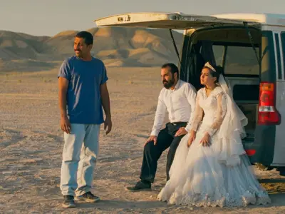 bride and groom sitting in the tailgate of an SUV in the desert 