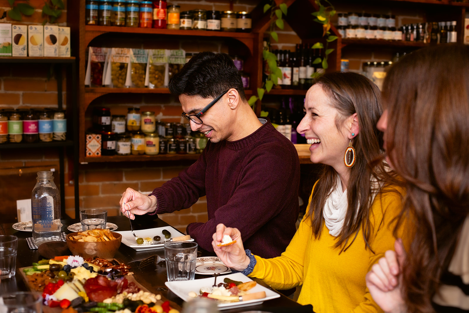 A group of people enjoying charcuterie at a large table in the Milk Maid restaurant.