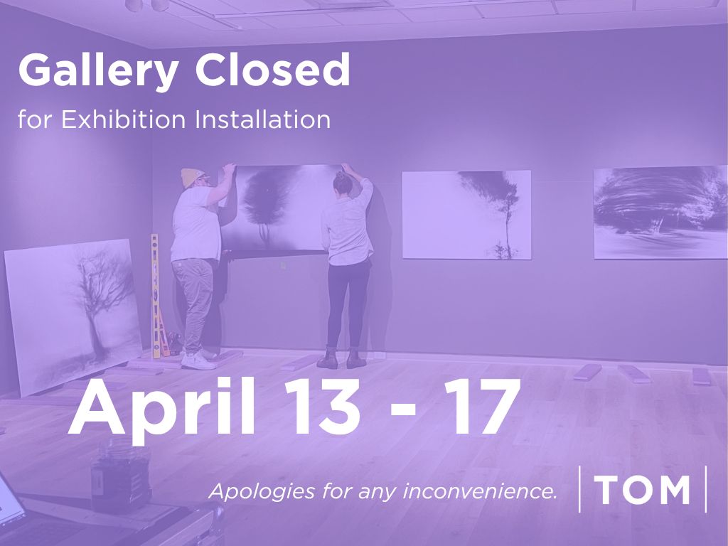 Image of two people installing art in the gallery space.