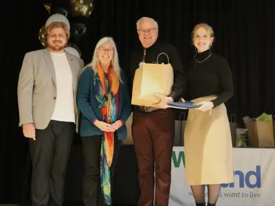Four people standing on stage presenting Colleen Purdon with her Lifetime Achievement Award