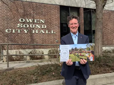 Mayor Boddy holding a copy of the new community profile print version