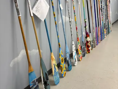 Paddles painted by local artists leaning on wall at The TOM